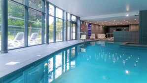 An indoor swimming pool with clear glass walls, lounge chairs, and a reception area. - Maison duplex avec wifi | Près de l'Aven (Pont-Aven)