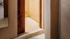 A hallway with a wooden door leading to a room, a light switch, and a shelf. - Surfnest Hostel (Brisas de Zicatela)
