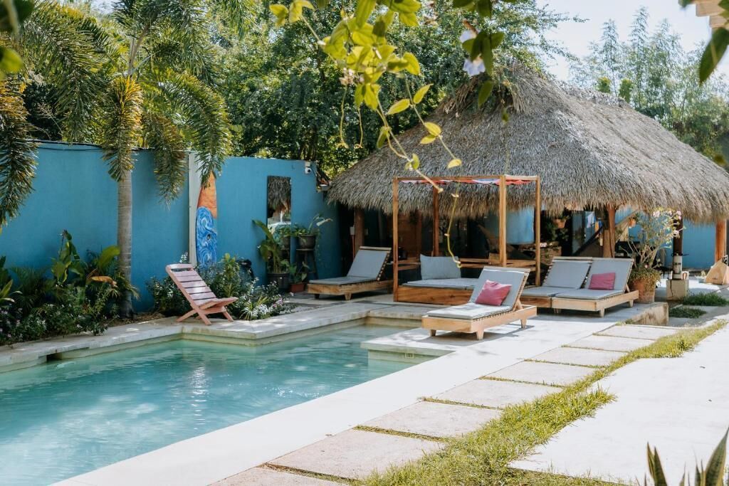 A pool area with lounge chairs and a thatched-roof structure.