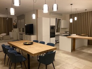Una cucina moderna con zona pranzo, TV e schermo piatto.
