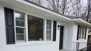 A white single-story house with a front porch, black railings, and a large black trash can. - Great House In Taylors Just Minutes To Downtown Greenville (Taylors)