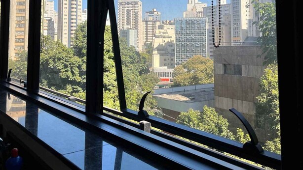 A view from a window with a cityscape, including high-rise buildings and greenery.