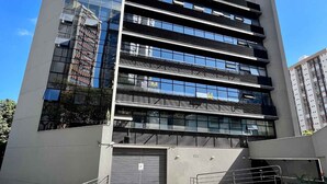 A modern building with multiple floors, large windows, and a gated entrance.
