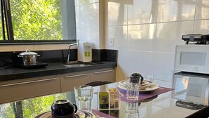 A modern kitchen with a glass island, stainless steel appliances, and a view of greenery outside.