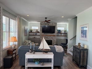 A living room with a fireplace, a television, and a sailboat model on a coffee table.