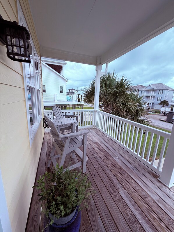 A wooden deck with a white railing, a bench, and a potted plant.