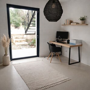 Ein moderner Arbeitsraum mit Schreibtisch, Stuhl, Computer und einer Pendelleuchte.
