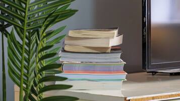 A desk with a stack of books, a keyboard, and a television.