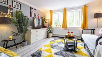 Une chambre moderne avec un lit, une table de chevet, une lampe, une fenêtre avec des rideaux, un radiateur et une plante.