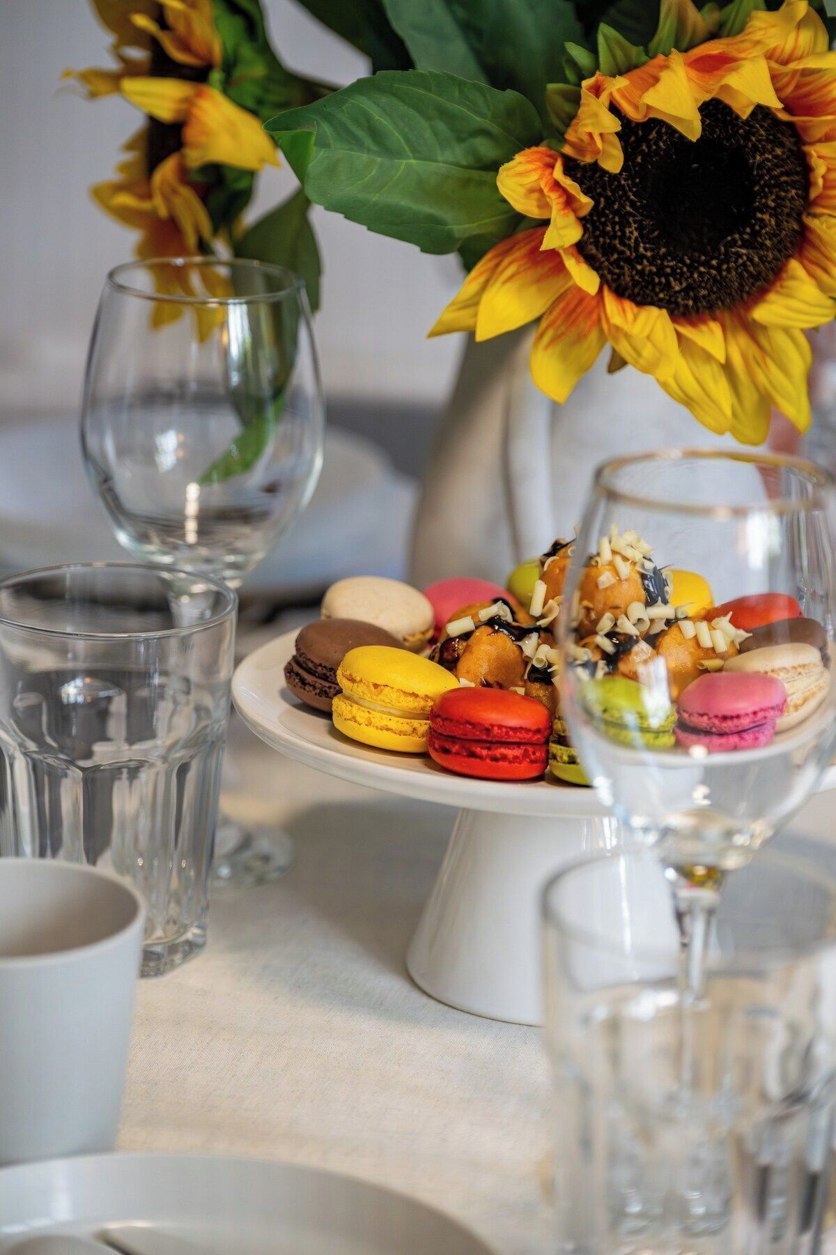Une table sur laquelle on trouve une variété de macarons et un vase rempli de tournesols.