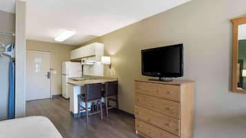 Una habitación de hotel compacta con kitchenette, televisión, cama y cómoda.
