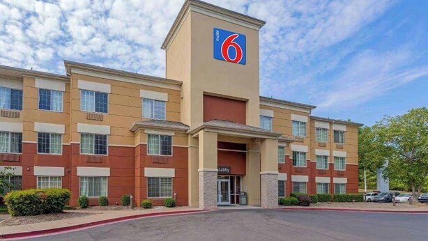 Un motel reconnaissable à son grand panneau indiquant le chiffre « 6 », à son entrée et à son parking.
