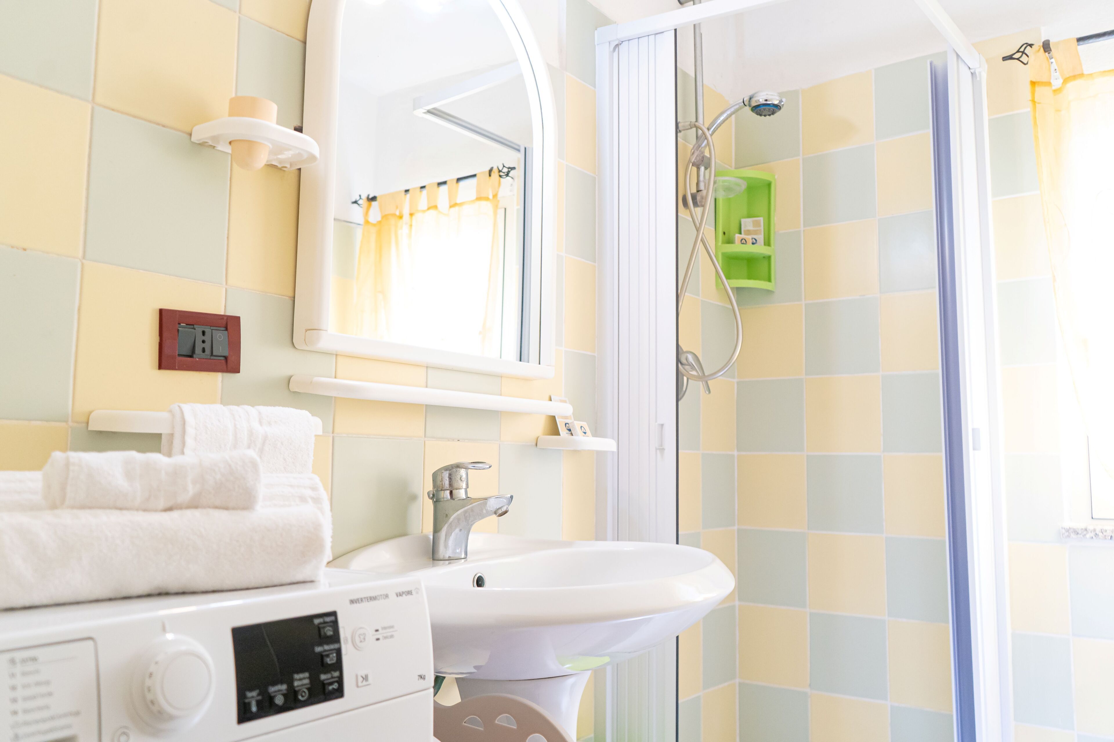 A bathroom with a sink, mirror, and shower.