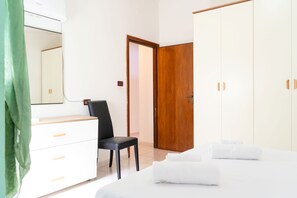 Ein Hotelzimmer mit Bett, Stuhl, Kommode, Schrank und Spiegel.