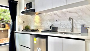 Une cuisine moderne équipée d’un four à micro-ondes encastré, d’une cuisinière à gaz et d’un évier en acier inoxydable.