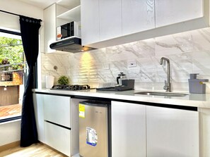 A modern kitchen with a built-in microwave, gas stove, and stainless steel sink. - TORRE PIZO URBANITY LIVING (Medellín)