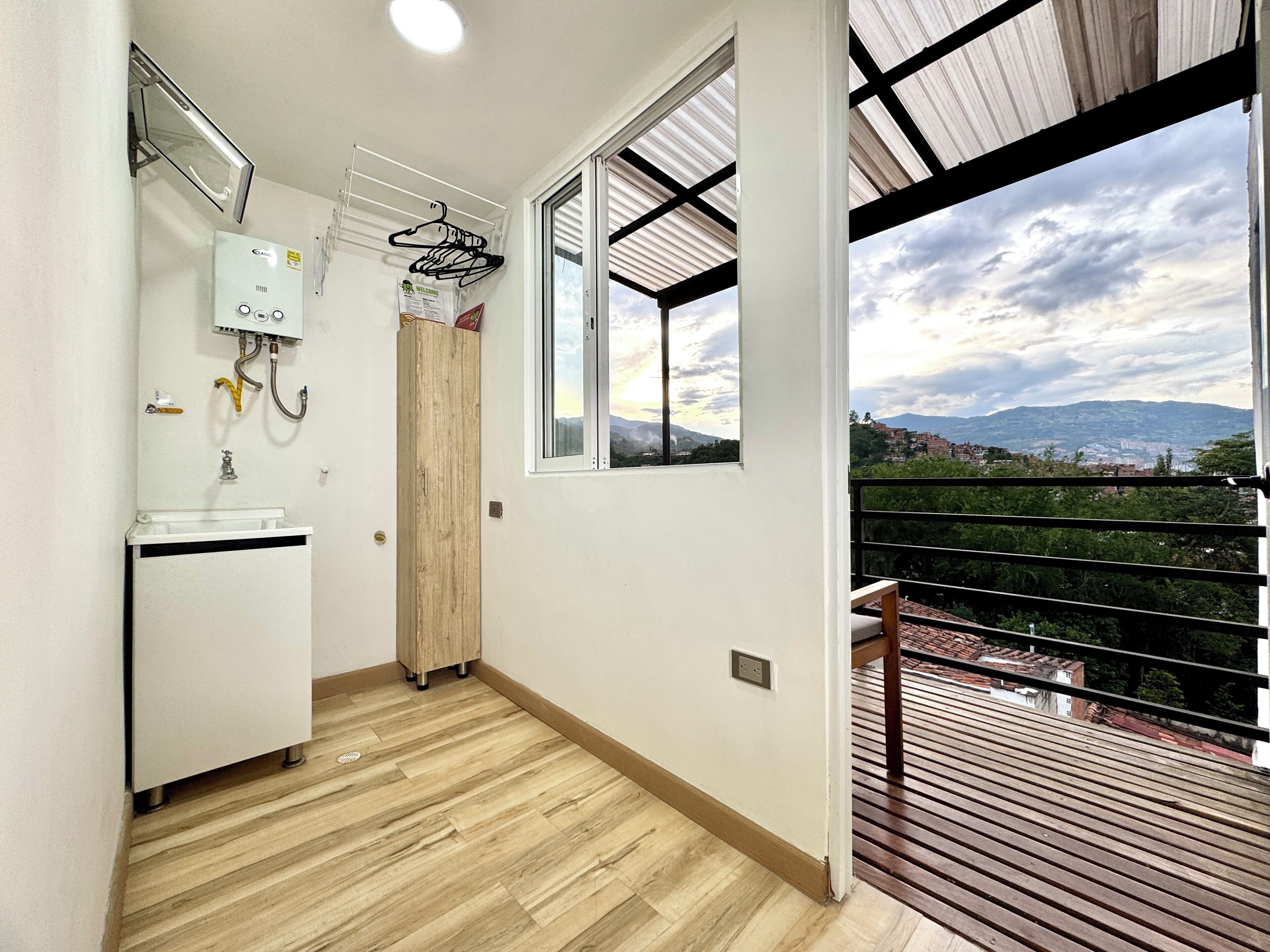 A bathroom with a wooden floor, a white sink, a towel rack, and a window with a view of a cityscape.