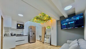 Une cuisine moderne dotée d’un réfrigérateur encastré, d’un coin repas avec un canapé et d’un téléviseur à écran plat fixé au mur.