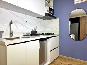 Uma cozinha moderna com painel de mármore, eletrodomésticos de aço inoxidável e piso de madeira.