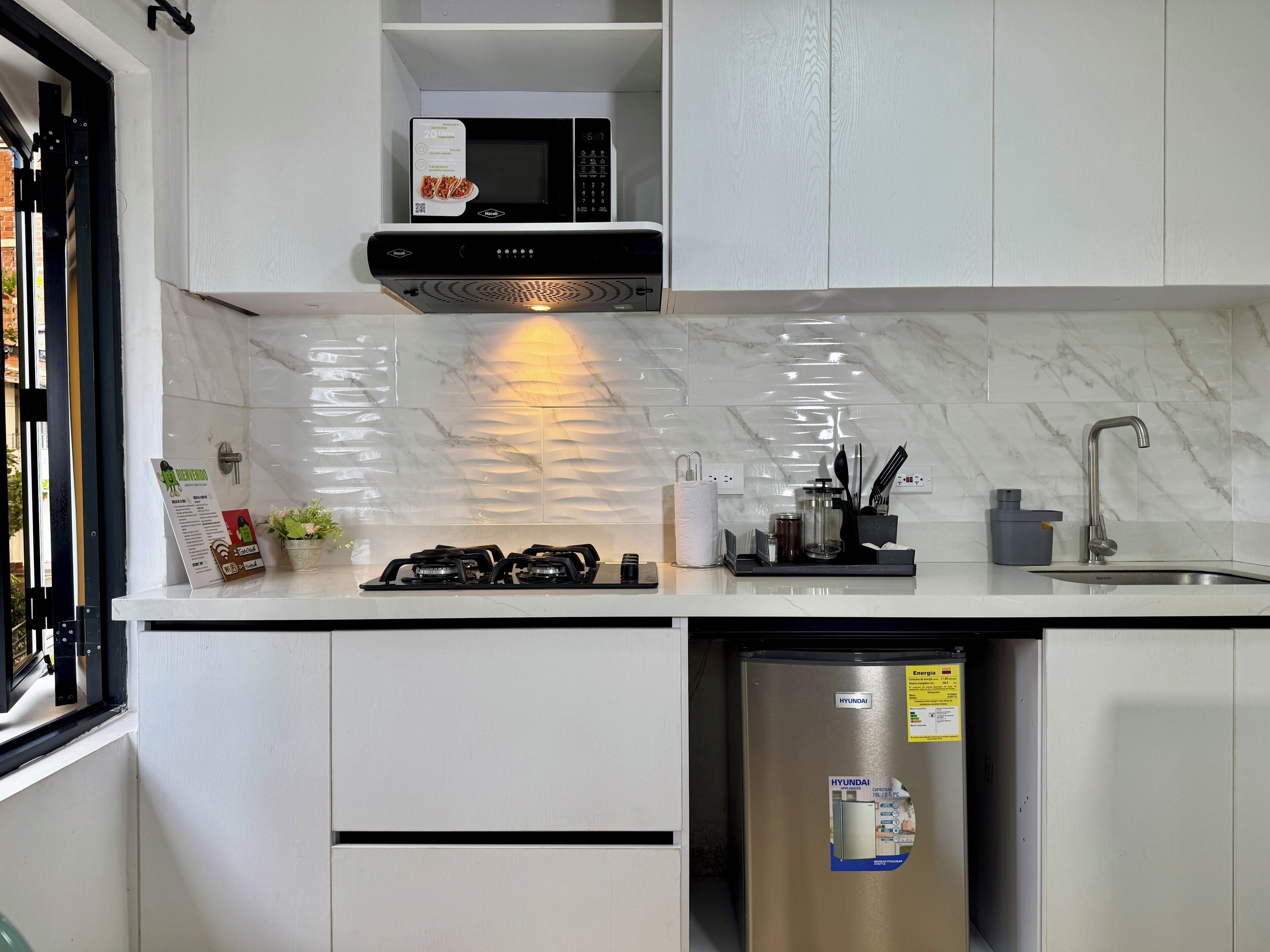 Una cocina moderna con microondas integrado, cocina a gas, refrigerador de acero inoxidable y salpicadero de mármol.
