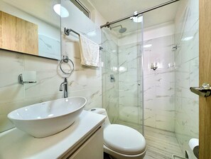 A bathroom with a glass-enclosed shower, a white sink, and a toilet. - TORRE PIZO URBANITY LIVING (Medellín)