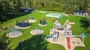 A playground with various play structures, a swimming pool, and a covered seating area. - Waterfront Holiday Home in Darlowo (Darlowo)