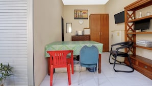 Una habitación con una cama, un escritorio, dos sillas, un televisor y una estantería.