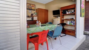 Un comedor con una mesa, sillas, un televisor y una estantería con varios objetos.