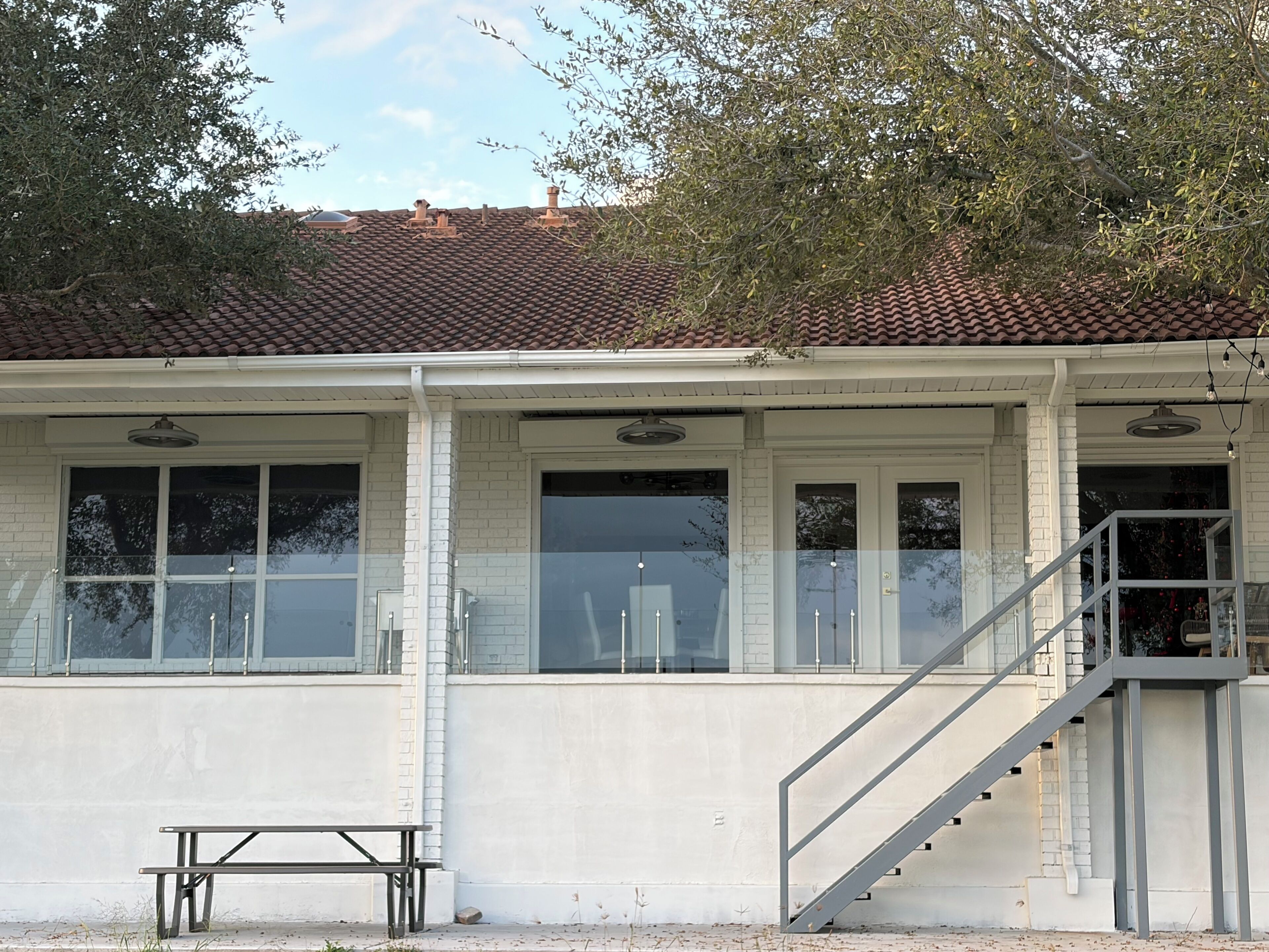 A building with a tiled roof, white brick walls, and a staircase leading to an upper level.