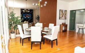 Un comedor moderno con una mesa redonda, sillas blancas y suelo de madera.