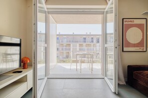 A room with a sliding glass door leading to an outdoor balcony with white chairs and a table. - New apt terrace, parking, garden, metro in 2 min (Milan)