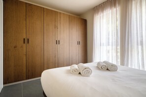 A bedroom with a large wooden wardrobe, a neatly made bed, and sheer curtains. - New apt terrace, parking, garden, metro in 2 min (Milan)