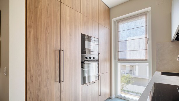 Eine moderne Küche mit Holzausstattung, einem eingebauten Backofen und einem Fenster mit Außenblick.