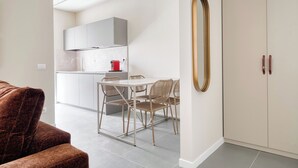 Eine moderne Küche mit weißen Schränken, einem Esstisch mit Stühlen und einem großen Spiegel an der Wand.