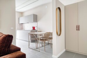 A modern kitchen with white cabinets, a dining table with chairs, and a large mirror on the wall. - New apt terrace, parking, garden, metro in 2 min (Milan)