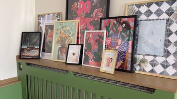 A display of framed artworks on a shelf above a green radiator.