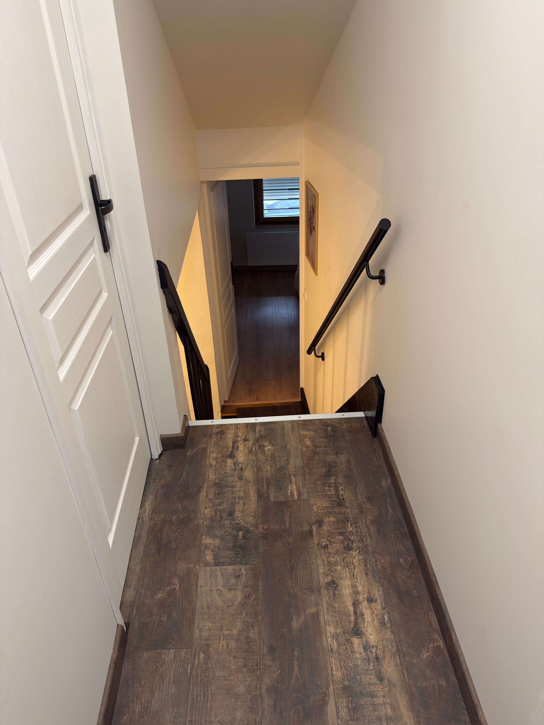 A narrow stairway with a dark wooden floor leading to a landing.