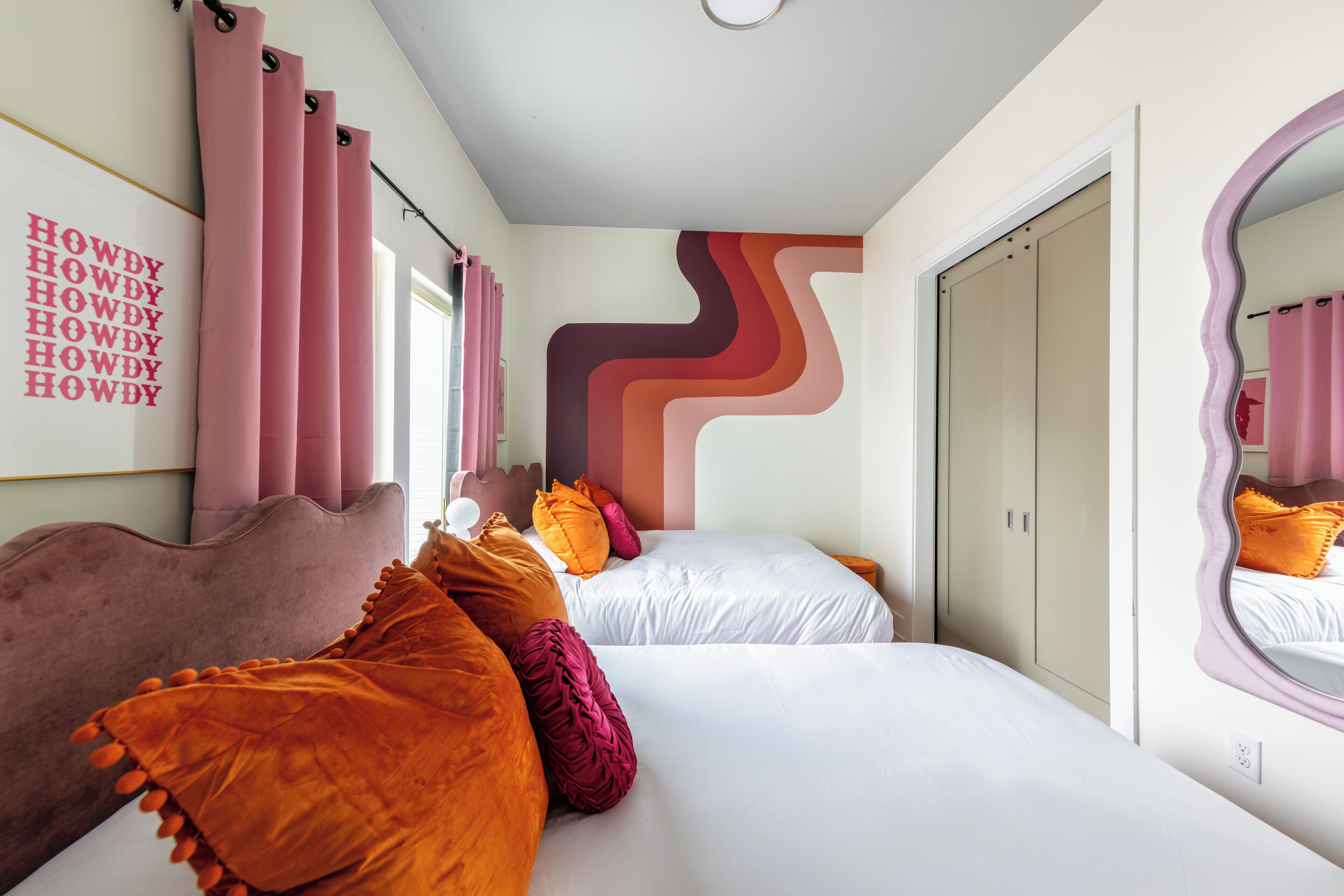 Een slaapkamer met twee bedden, een spiegel en een wand met een uniek ontwerp.