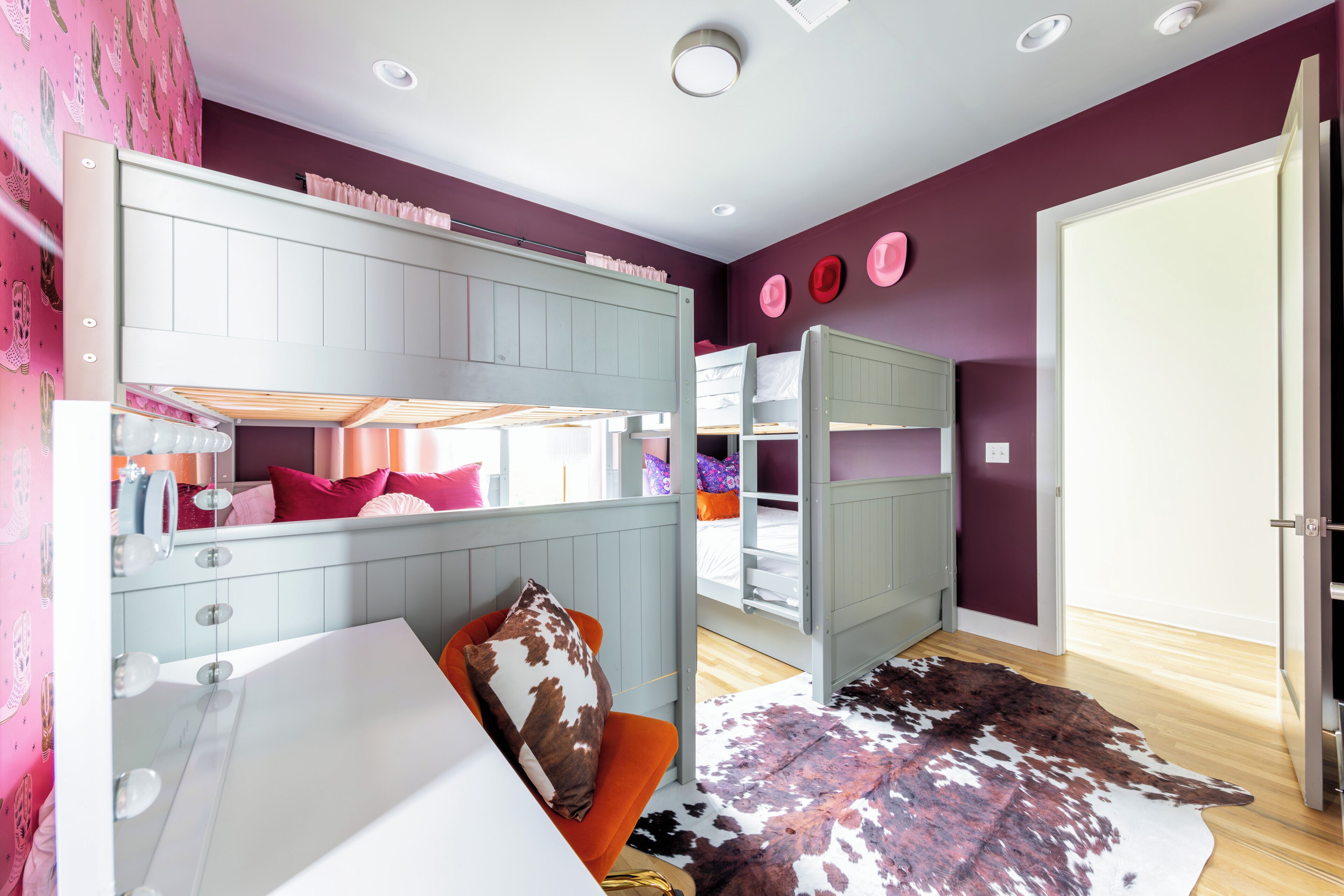 A bedroom with bunk beds, a vanity, and a cowhide rug.