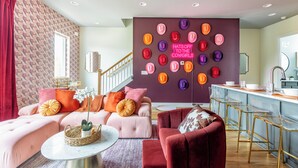 Una sala moderna con un sofá, un sillón rojo, una mesa de centro y una pared con un letrero de neón.