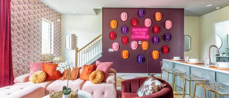 A modern living room with a sofa, a red armchair, a coffee table, and a wall with a neon sign.
