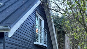 Un edificio negro con un banco, una ventana y un árbol al fondo.