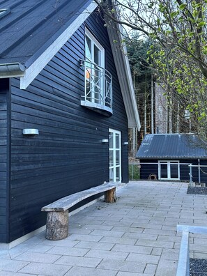 Un bâtiment noir avec un banc, une fenêtre et une porte.