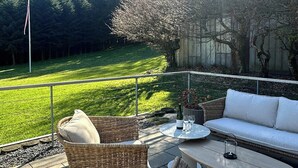 Un patio exterior con mobiliario de mimbre, una mesa y un sofá.