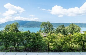 Ein See mit Bergen im Hintergrund, umgeben von Bäumen und einem klaren Himmel.