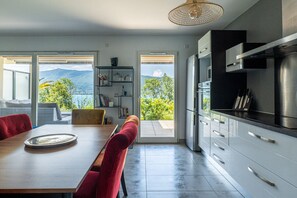 Eine moderne Küche mit Bergblick, ein Essbereich mit roten Stühlen und ein großes Fenster.
