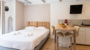 Ein Hotelzimmer mit Bett, Schreibtisch, Stuhl, Fernseher und einer Küchenzeile.