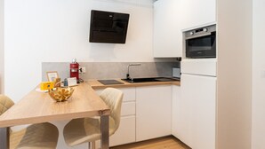 Eine kompakte Küche mit eingebautem Backofen, einer Wandklimaanlage und einem Holzessttisch mit Stühlen.