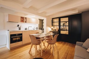 Eine moderne Küche mit Essbereich, Holzboden und einem Wohnzimmer in dunklen Tönen.