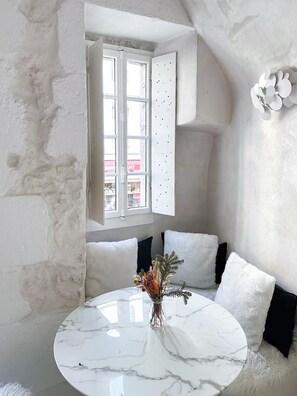 Ein Zimmer mit Marmortisch, weißen Wänden und einem Fenster mit Jalousien.